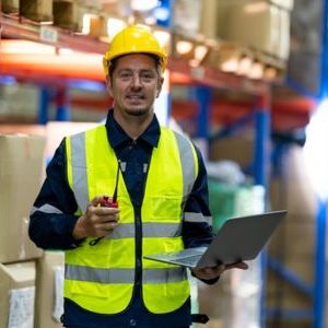 Immagine che mostra una uomo all'interno di un grande magazzino che in mano ha un piccolo computer e un walkie talkie. È usata come immagine del corso gratuito "MAGAZZINIERE" del progetto GOL