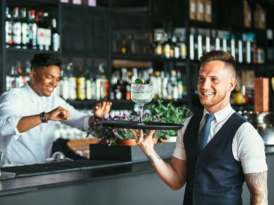 Immagine che mostra una ragazzo mentre porta un cocktail su un vassoio. È usata come immagine del corso gratuito "ADDETTO SALA E CAMERIERE" del progetto GOL