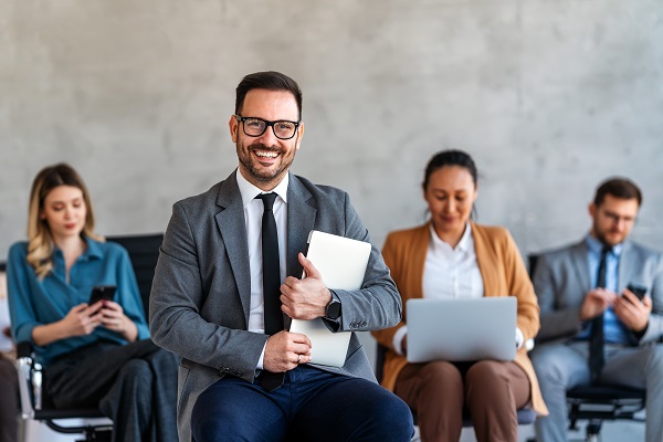 persona di sesso maschile sorridente con occhiali. è vestito con look da ufficio e ha in mano un tablet